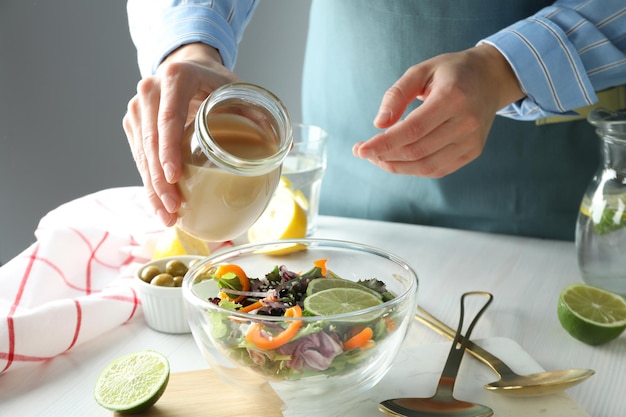 Concetto di cucinare insalata di verdure con salsa tahini su tavolo di legno bianco