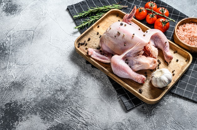 Concept of cooking whole chicken. Ingredients rosemary, pink salt, garlic and cherry tomatoes. Top view.