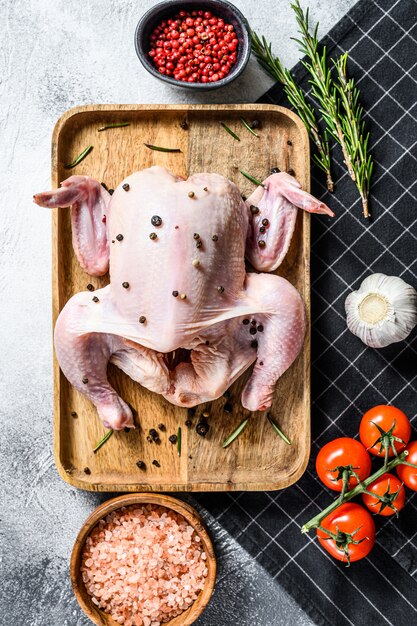 Concetto di cottura di pollo intero. ingredienti rosmarino, sale rosa, aglio e pomodorini. vista dall'alto.