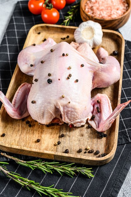 Concept of cooking whole poult. Ingredients rosemary, pink salt, garlic and cherry tomatoes.