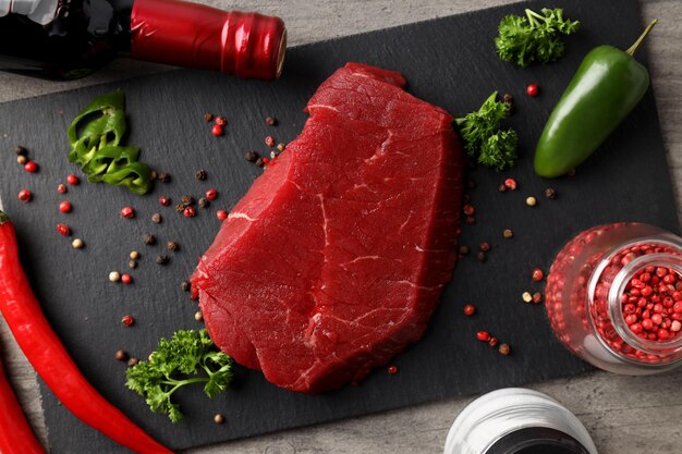 Concept of cooking with raw beef steak on gray textured background