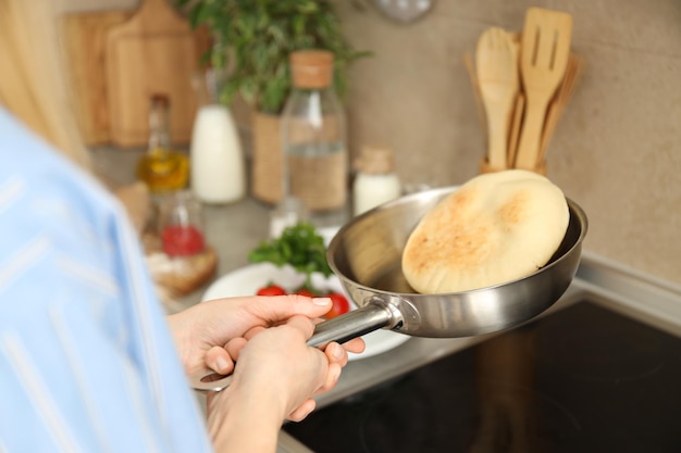 Il concetto di cucinare con la donna lancia la focaccia sulla padella