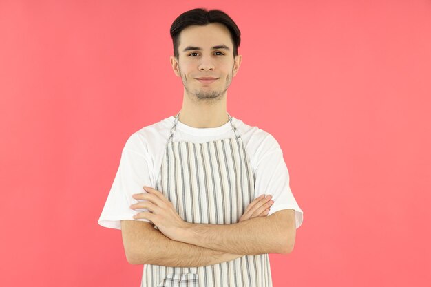 ピンクの背景に若い男のシェフを調理する概念