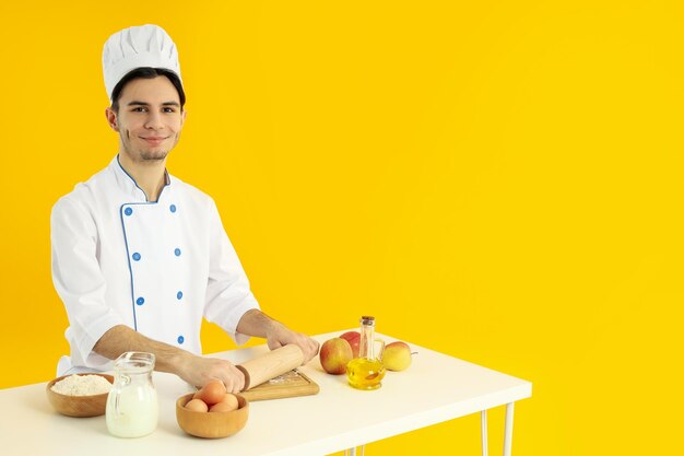 Concept of cooking young man chef on yellow background