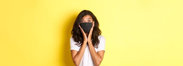 Photo concept of coronavirus pandemic and lifestyle portrait of excited africanamerican woman in face mask