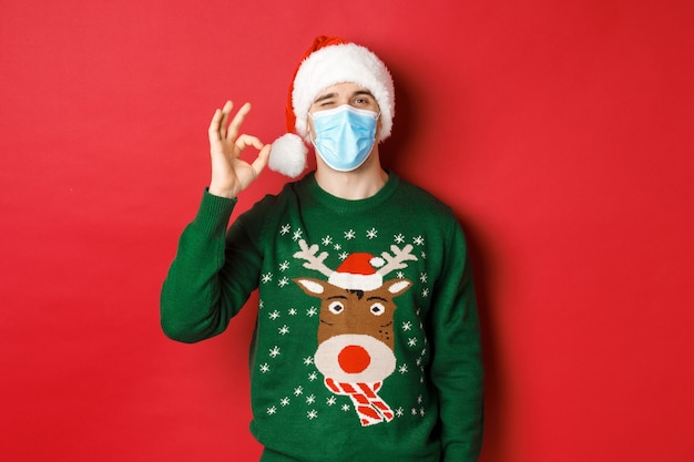 Concept of covid-19 and Christmas holidays with handsome young man wearing a mask