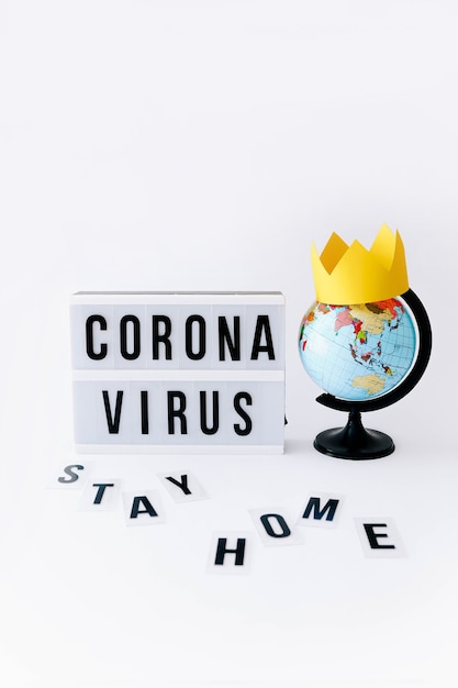 Photo concept of covid 19, corona virus text on display in lightbox and globe with crown on it, light table.