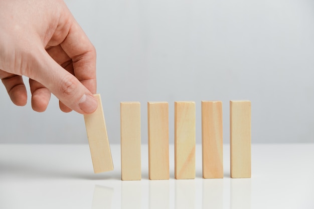 The concept of creating a phased business. Hand holds wooden blocks on a white space.