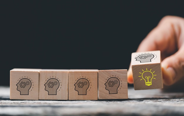 Concept creative idea and innovation hand choose wooden cube
block with head human symbol and light bulb icon knowledge and
education concept learning with smart technology