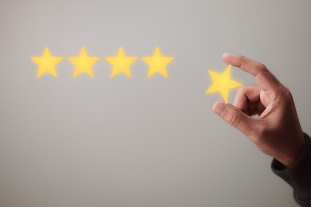 Concept of customer satisfaction and product service review\
holding the yellow star in your hand