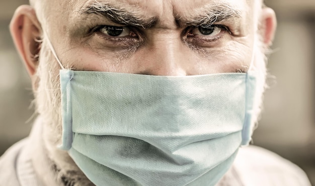 Понятие опасности коронавируса для пожилых людей. Коронавирус, болезнь, инфекция, карантин, медицинская маска. Старик в маске для лица. Крупный план.