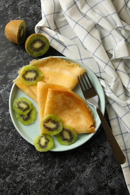 Concept of delicious breakfast with crepes with kiwi on black smokey background