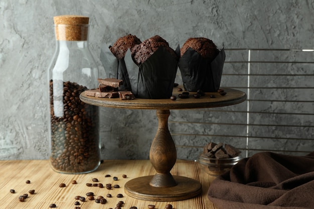 Concept of delicious food with chocolate muffins against gray background.