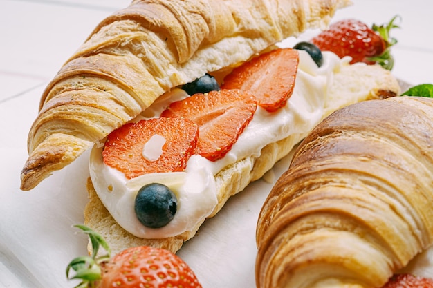 Concept dessert croissant met aardbeien en room op een lichte houten achtergrond