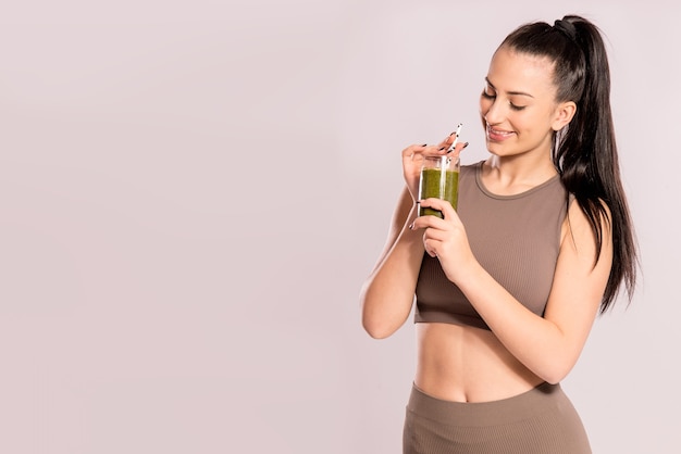 Concetto di disintossicazione, dieta sana e fitness. giovane donna che tiene un bicchiere con frullato verde.
