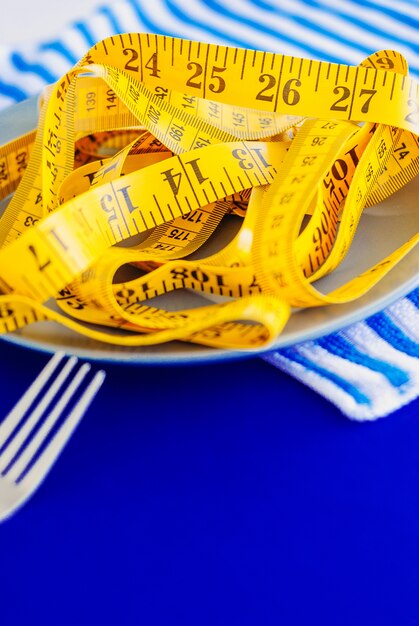 The concept of the diet. The fork rewound centimeter lying on plate closeup