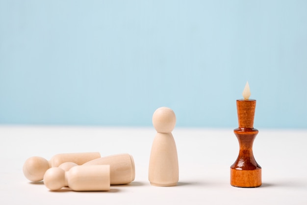 The concept of dismissal of employees. The figure of the wooden king on a blue background looks at the figures.