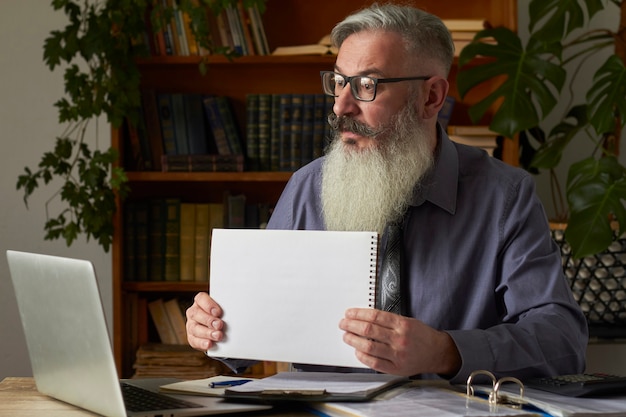 Concetto di apprendimento a distanza. insegnante, traduttore, tutor sul desktop della biblioteca mostra un piatto bianco sullo schermo del laptop