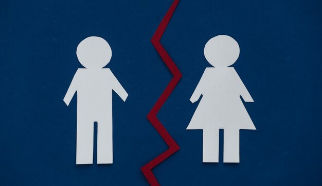 Foto il concetto di divorzio. le figure di carta dell'uomo e della donna sono divise su un classico blu.