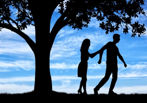 The concept of divorce and parting of a married couple. Silhouette of a man throwing a woman near a tree