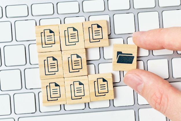 Photo concept document management system or dms. the person archives files in a folder. hand and cubes on the keyboard.