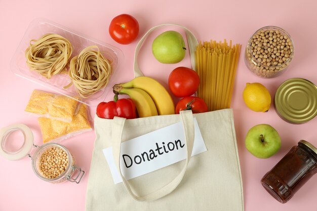 Concept of donation with food on pink background