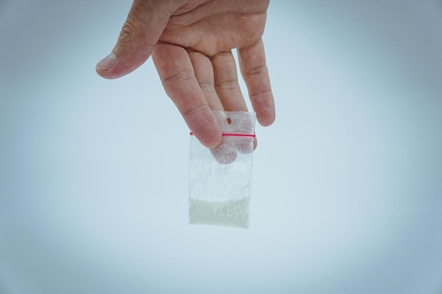 Concept drug addiction. Man hand holds plastic packet or bag with cocaine or another drugs.