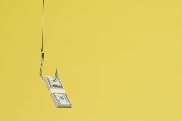 The concept of earning money a wad of dollars on an iron hook on a yellow background copy paste