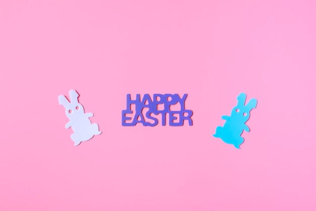 Concept for Easter card, banner or invitation. On a pink background, rabbits with an inscription close up with copy space.