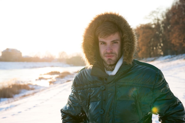 Concept ecology male in down coat with fur hood feel warm and comfortable favorite season handsome guy green puffer coat man enjoy sunny winter day male seasonal fashion cold and flu