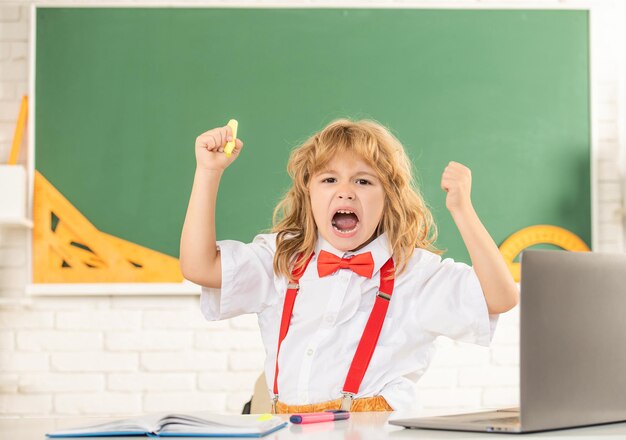 Concept of education. nerd kid with long hair at blackboard. september 1. childhood development. angry child studying writing. shouting teen boy in classroom. back to school. knowledge day.