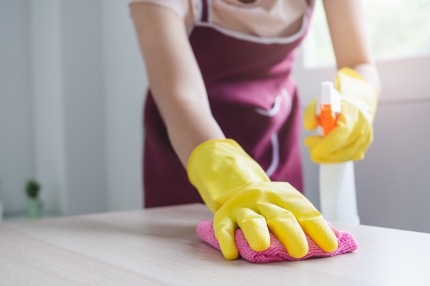 Concept een dag van huisvrouwenactiviteiten thuis. Sluit omhoog meningspersoon gebruikend een microvezeldoek veegstof op de lijst.