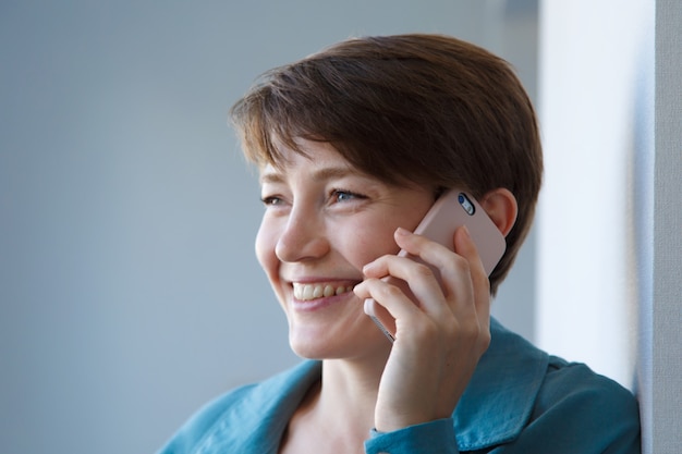 The concept of employment, interviews, advertising digital technology - woman talking on the phone. Smiling woman makes a call. Isolated on white background. Copy space