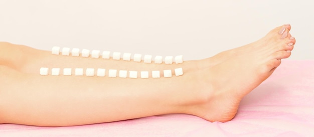 The concept of epilation waxing sugar cubes lie down in a row\
on the naked white female leg