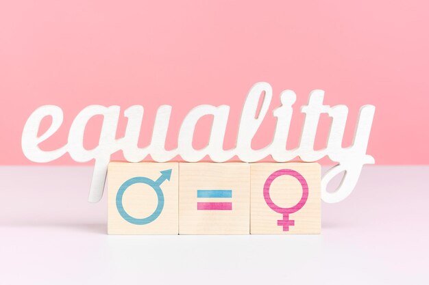 The concept of equal pay the word equality stands on three\
wooden cubes with the inscription pay closeup pink background