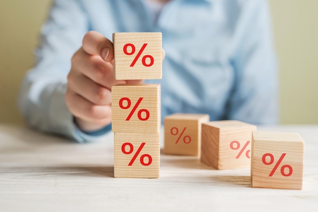 Concept of financial and mortgage interest rates Hand putting wooden cube block increasing from above with icon percent symbol up