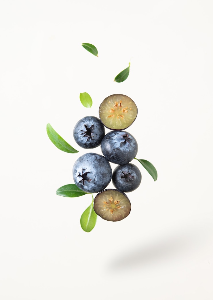 Photo concept flat lay with a  few juicy blueberries levitation with green leaves on yellow background. front view and copy space  image