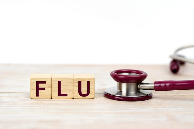 Concept of FLU word on Wooden cube with stethoscope Medical health care Health insurance