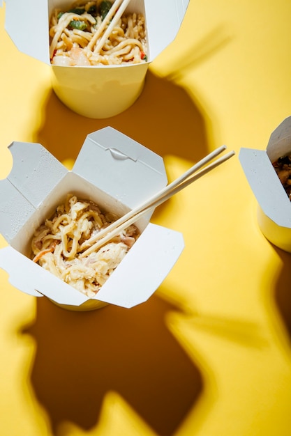 the concept of food delivery on a yellow background  noodles in boxes