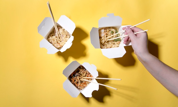 the concept of food delivery on a yellow background  noodles in boxes