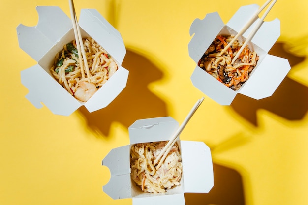 the concept of food delivery on a yellow background  noodles in boxes