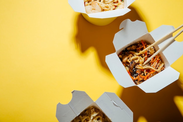 the concept of food delivery on a yellow background  noodles in boxes