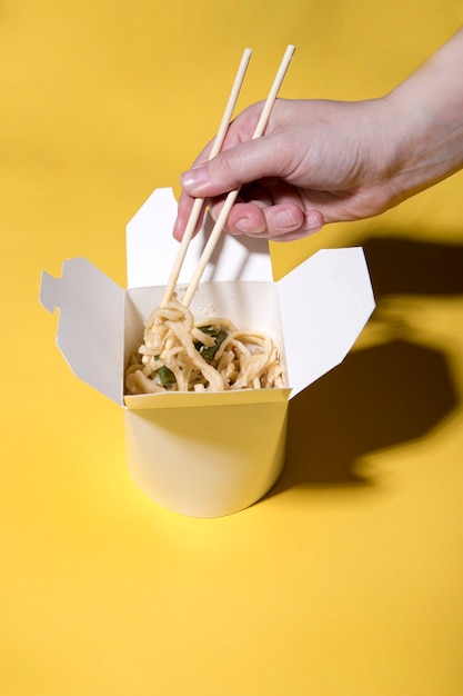 the concept of food delivery on a yellow background  noodles in boxes