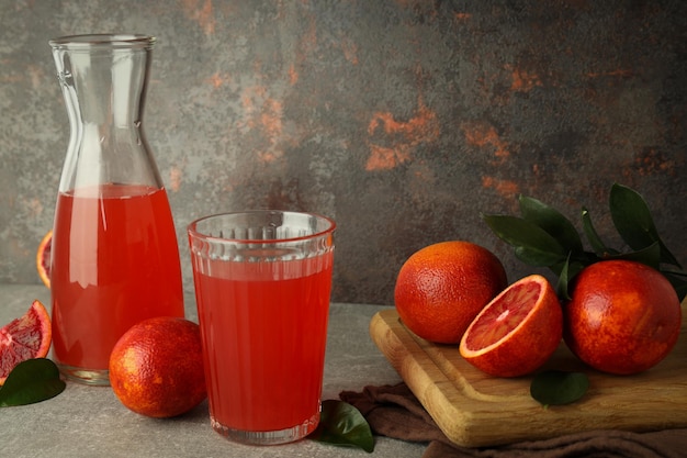 Concept of fresh drink with red orange juice on gray textured table