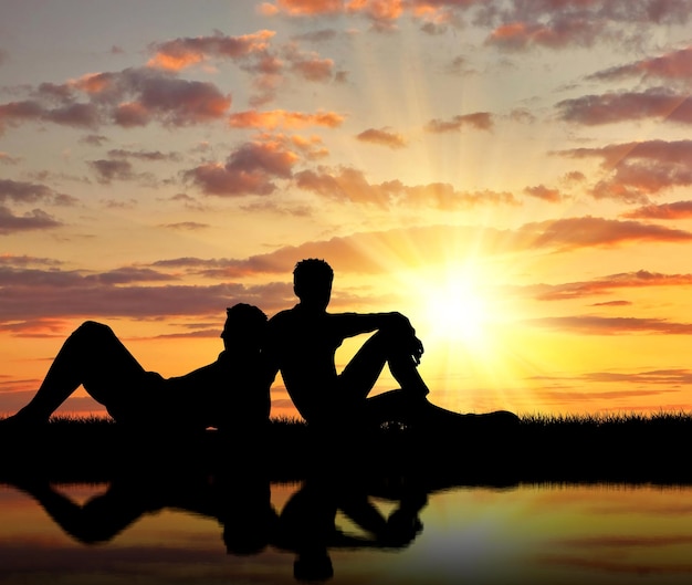 Photo concept of gay people. silhouette of two gay holidaymakers near the river at sunset