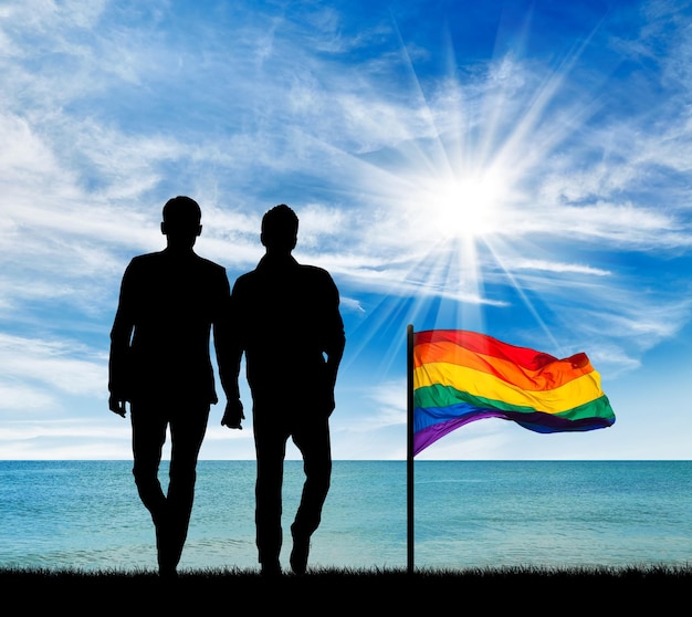 Concept of gay people. Silhouette of two gay men on a walk by the sea during the day and a rainbow flag