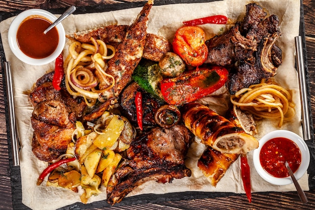 Concept of georgian cuisine. large meat board with shashlik, roasted meat, french fries, roast lamb and sauce. serving dishes in a restaurant on a pita. top view, copy space