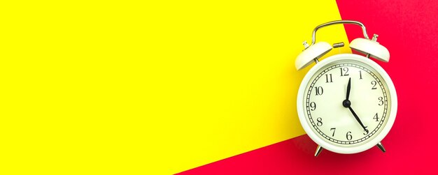 Photo concept of good morning, banner with white alarm clock on a colorful and bright background, copy space and top view photo
