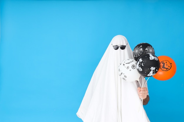 Photo concept of halloween ghost in sunglasses on blue background