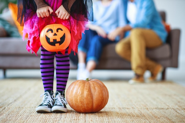 Concept of Halloween little child girl legs in witch costume with pumpkin